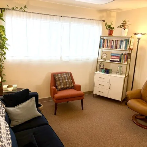 Mary Beth's office with a couch, armchairs, plants and bookshelves