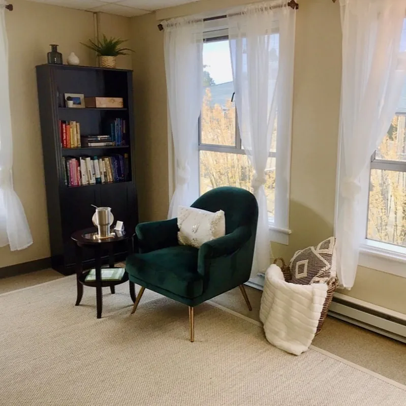 Kendall Thornton's therapy office with green armchairs, bookshelves and tall windows
